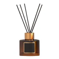 Difusor de aromas en frasco de cristal ámbar con detalles dorados y varillas negras, excelente como material promocional para regalos corporativos y de bienestar